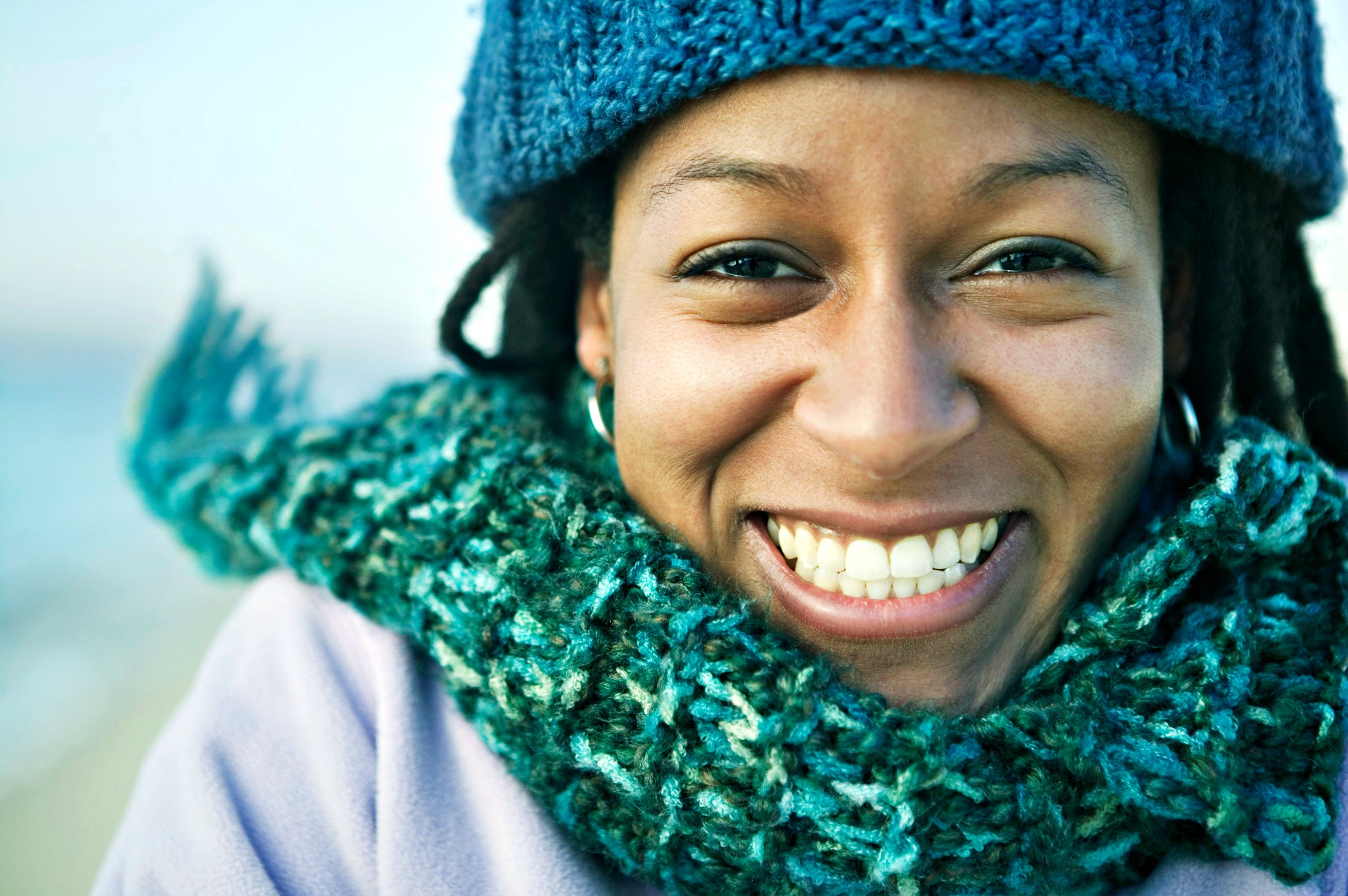 Smiling African American woman with a teal hat and scarf, beaming directly at the camera.