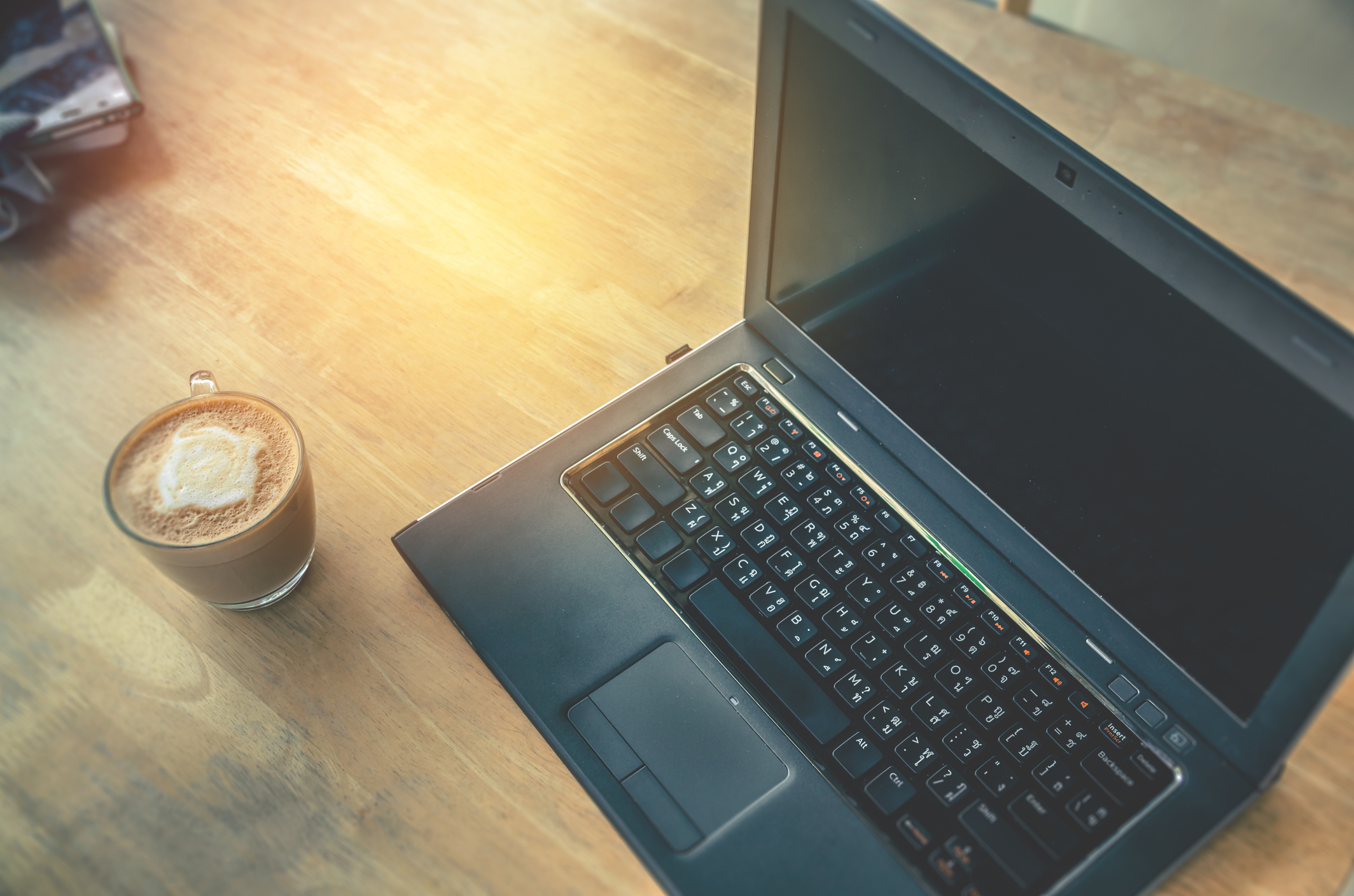 Laptop computer on a desk next to a coffee